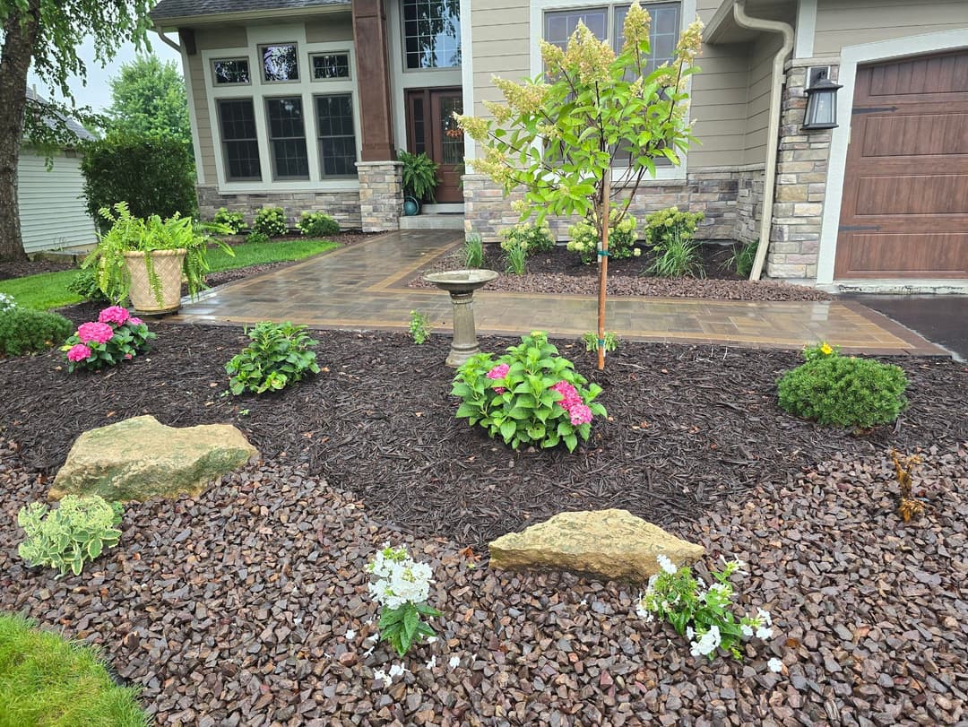 Beautiful landscaped front yard with vibrant flowers, decorative stones, and a birdbath.