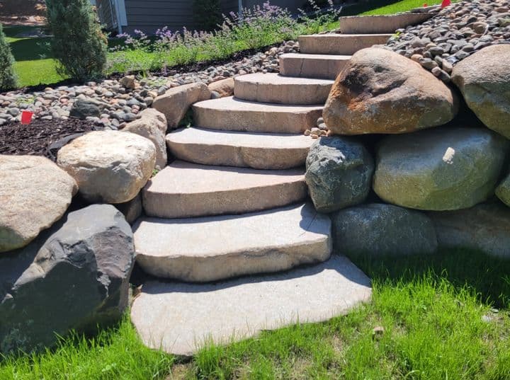 Elegant stone steps leading up a landscaped garden with natural boulders and greenery.