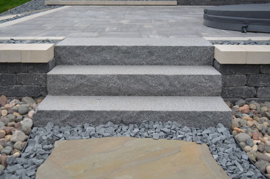 Granite steps leading to a patio, surrounded by decorative gravel and stone.