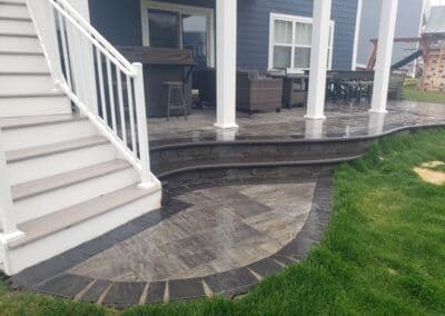 Patio with stylish stone design, steps, and modern outdoor furniture in a backyard setting.