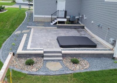 Paved patio with steps, surrounded by decorative stones and landscaping features.